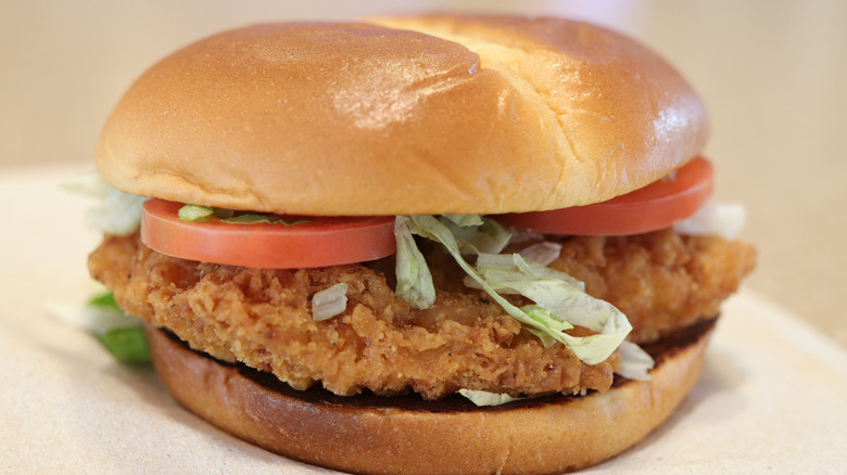 McDonald's Spicy Deluxe McCrispy with shredded lettuce, Roma tomatoes, spicy pepper sauce, and crunchy chicken patty on a bun.