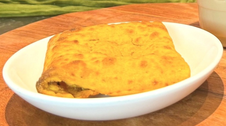 Starbucks' new Jalapeño Chicken Pocket on a white plate on a wood charger.