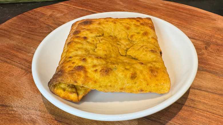 Starbucks' new Jalapeño Chicken Pocket on a white plate on a wood charger.