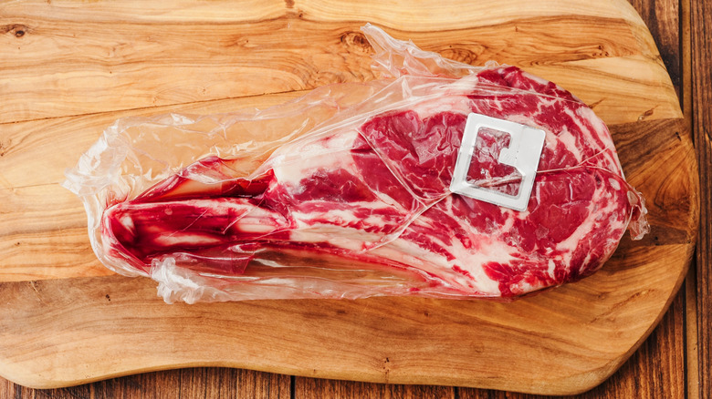 A vacuum-sealed steak on a wooden cutting board