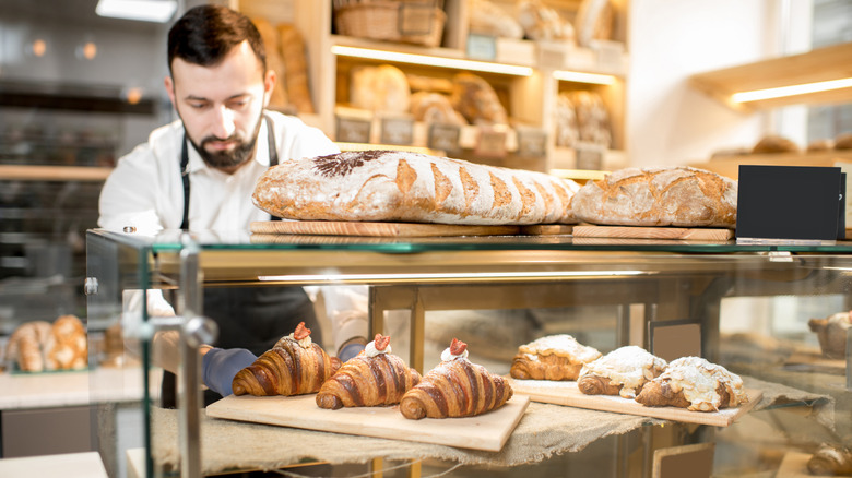 A bakery employee stocking fresh pastries