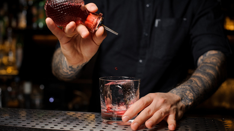 man pouring bitters into glass