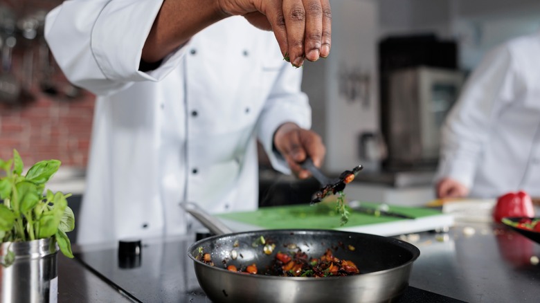 Chef seasoning dish in restaurant kitchen