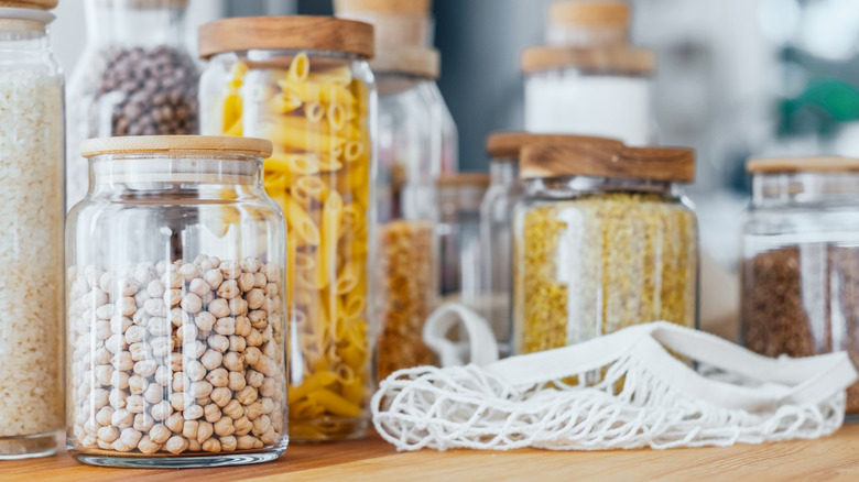 Glass jars of dry goods on a wooden table.