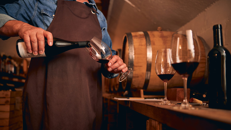 winemaker in cellar pouring wine