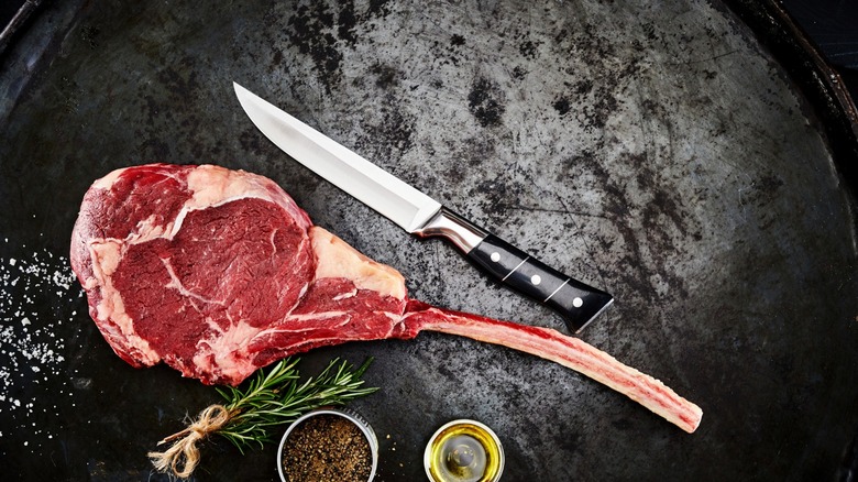 Ribeye Delmonico stake on black cutting board with knife