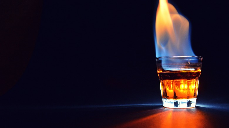 Shot glass full of flaming brown liquor