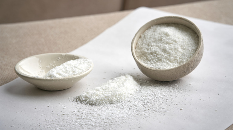 Bowls of white powder with more powder spilled onto parchment paper
