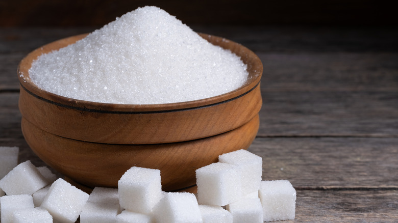 A bowl of granulated sugar with sugar cubes in the foreground