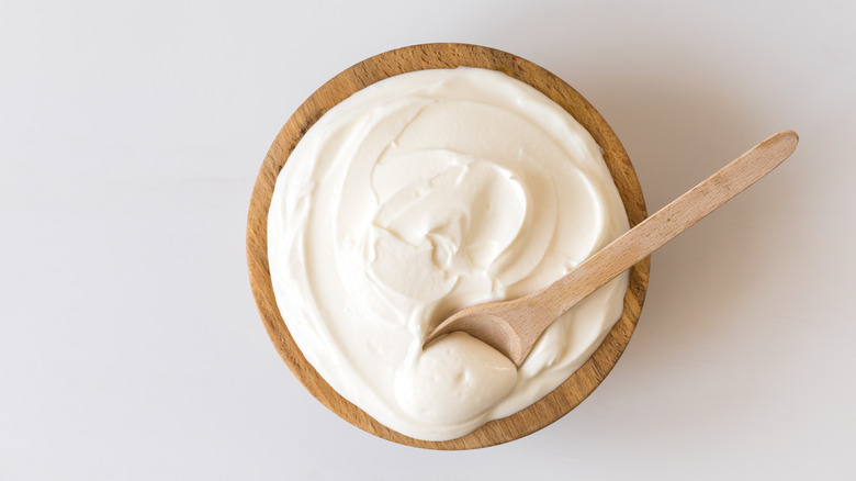 A wooden bowl of yogurt with spoon