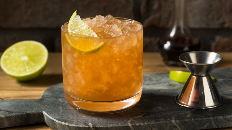 Corn 'n' oil cocktail with jigger and sliced lime