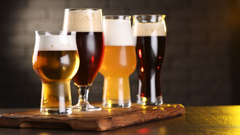 Various beer glasses aligned on a wood board