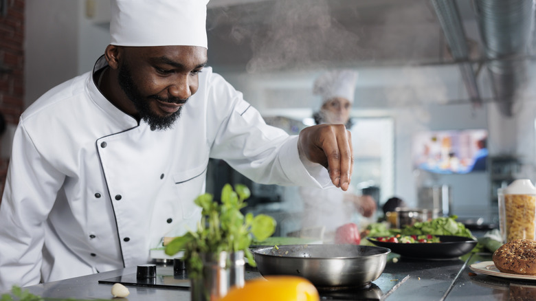 Chef adding seasoning to food