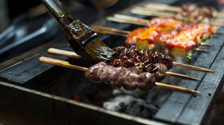 Brushing sauce onto Japanese barbecue skewers