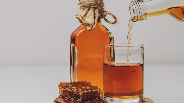 pouring a glass of mead next to honeycomb