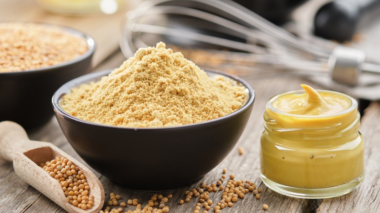 Ramekin of mustard powder and jar of yellow mustard