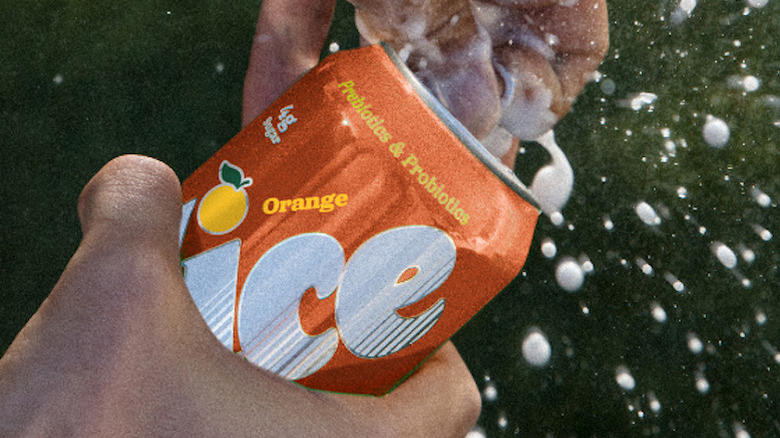 A can of Slice orange soda being opened and spraying foam