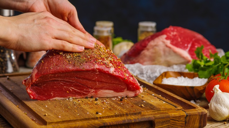 Seasoning beef on a wooden board