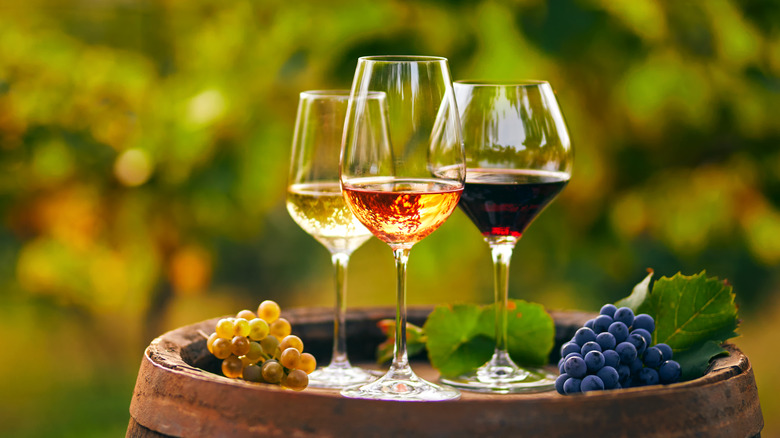 Three glasses of wine with grapes on a barrel