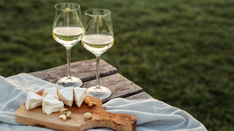 Two glasses of white wine with cheese on a wooden table