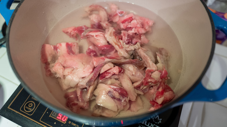 Chunks of beef fat melting in deep pot