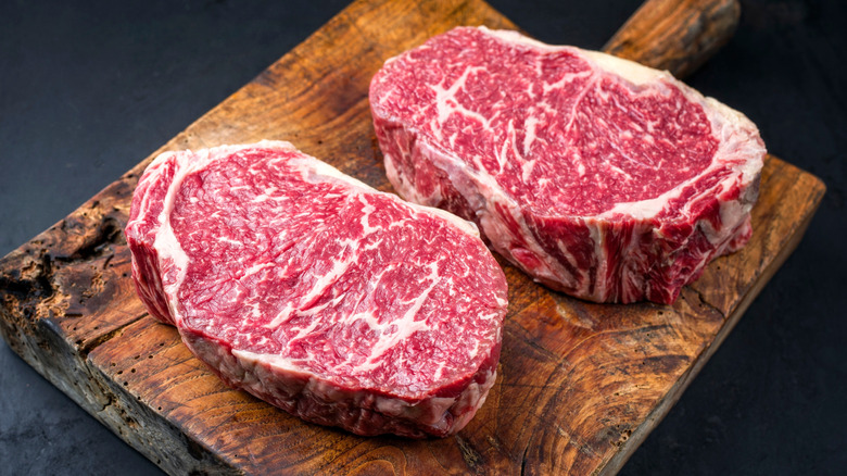 Two marbled steaks on wooden cutting board