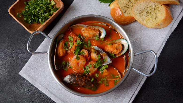 French seafood bouillabaisse stew in an iron pot with bread
