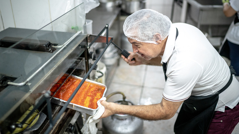 chef putting lasagna in oven