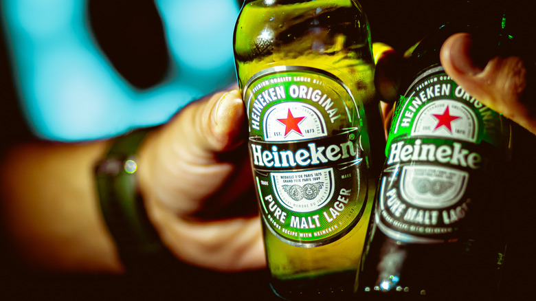 toasting with two Heineken bottles