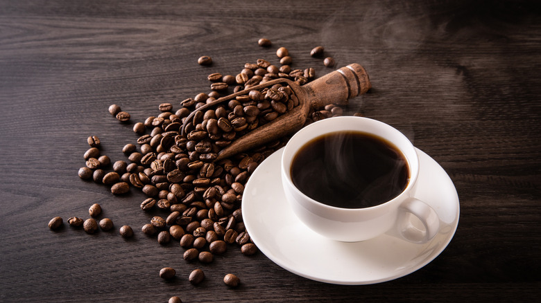 Cup of coffee surrounded by coffee beans