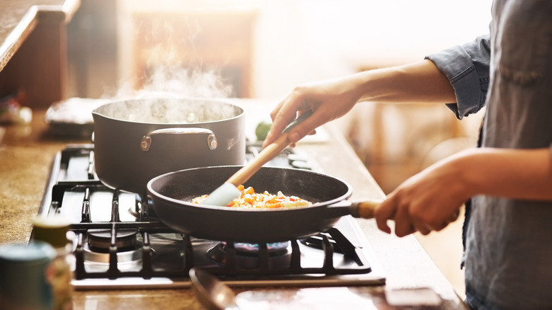 A person cooking food in a skillet on the stove