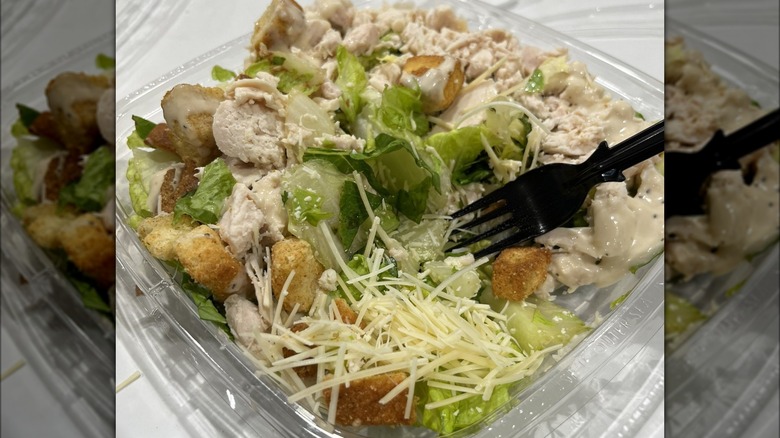 Costco Caesar salad topped with chicken open fork