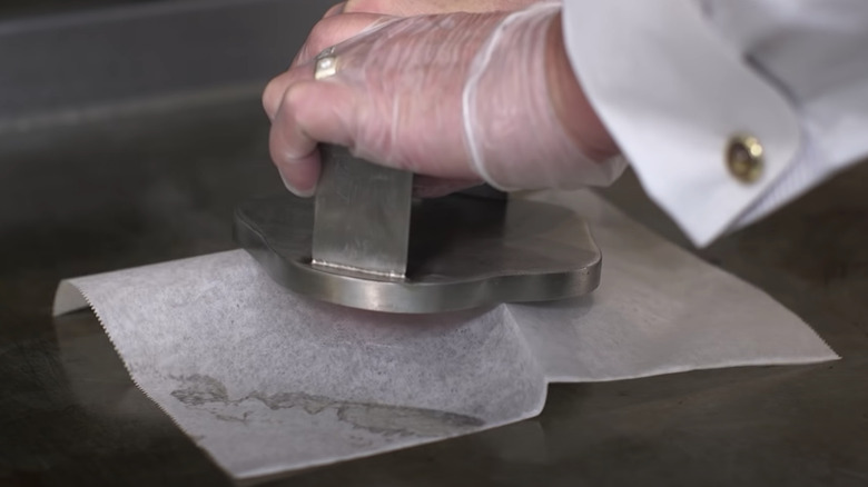 hands mashing a smashburger on griddle