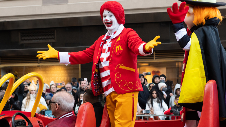Ronald McDonald and the Hamburglar riding in a red car