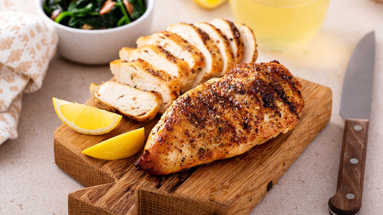 Grilled chicken sliced up on a wooden cutting board