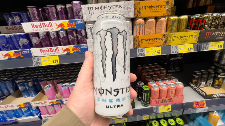 Person holding a can of Monster Ultra White in a store