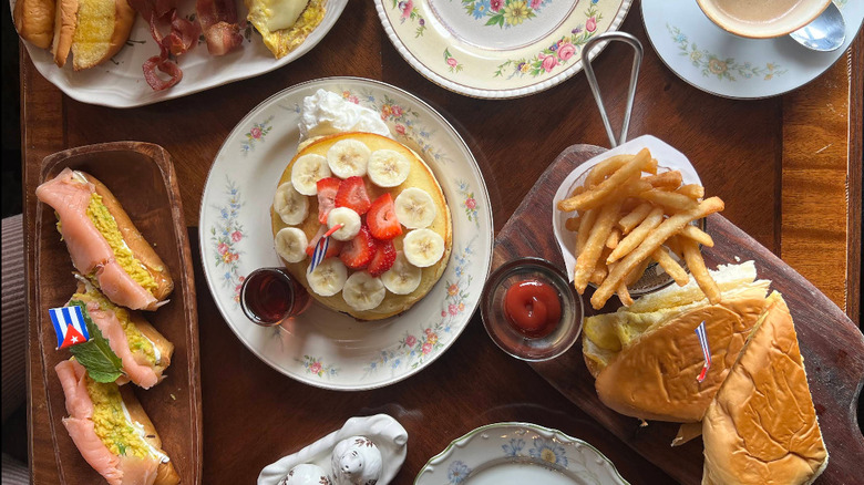 A spread of Cuban food at hole in the wall Habana con B in Miami, including Cuban sandwiches, pancakes, breakfast items and french fries.