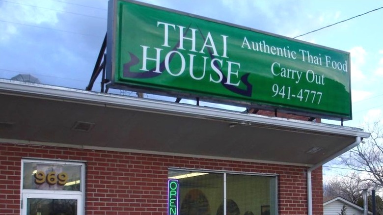 The exterior sign of Thai House restaurant in Wichita, Kansas boasts their authentic thai food and carry out options.
