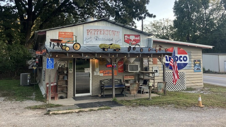 The Peppertown Restaurant in Mantachie, Mississippi has the look of an old roadside gas station, covered in vintage metal signs and yard decor, with the unique look of a backroads hole in the wall restaurant.