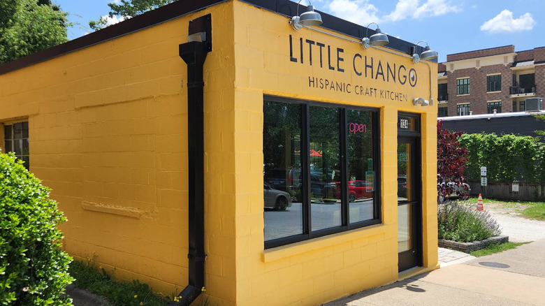 A small, cheerful yellow cinderblock building, painted with the words Little Chango Hispanic Craft Kitchen in downtown Asheville North Carolina.