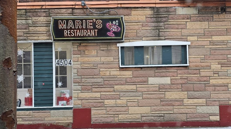 Unassuming exterior of Marie's in Cleveland, with a neon sign announcing its name next to an illustration of a cocktail glass.