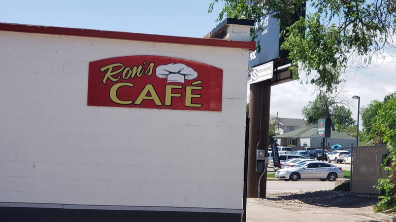 A diner style sign for Ron's Cafe on the side of an unassuming cinderblock building.