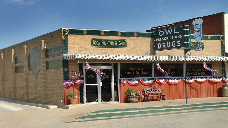 The outside of Owl Drugs advertises its classic 1920's style soda fountain and diner along with its pharmacy offerings.