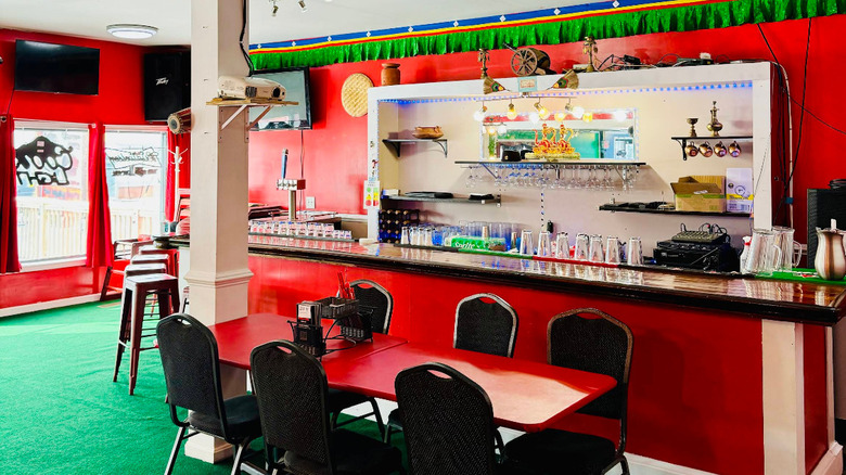 The red-walled interior of Delight Indian restaurant in Burlington, Vermont is sparsely adorned with green decorations and brass wares.
