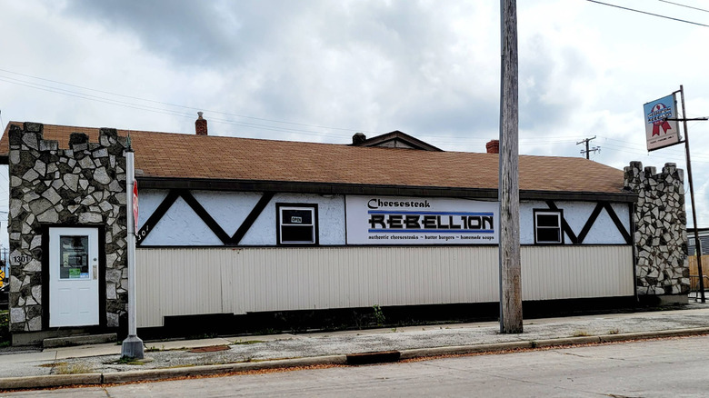 The exterior of the cobblestone and stucco building of Cheesesteak Rebellion in Green Bay, Wisconsin.
