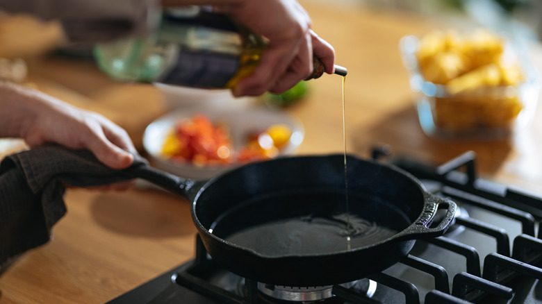 Person adding oil to a cast iron skillet.