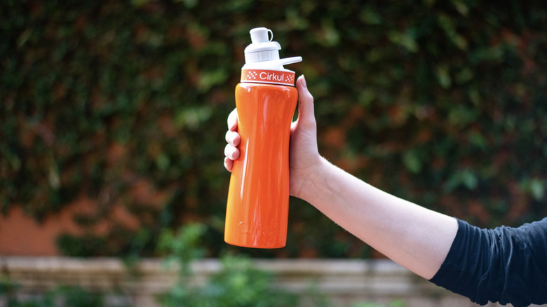 Person holding orange Cirkul water bottle