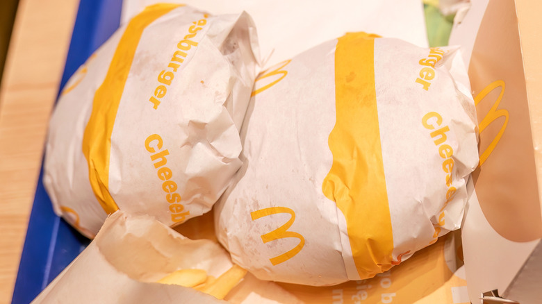Two McDonald's cheeseburgers in their white paper wrapping with yellow text