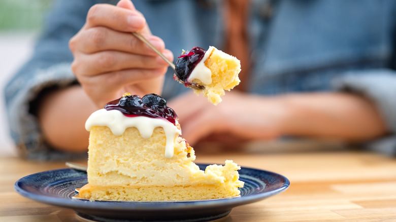 Woman eating slice of cheesecake