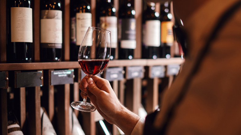 person holding glass of wine in wine shop